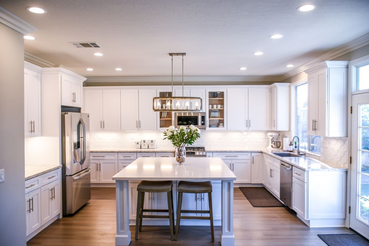 Spacious white kitchen with a thick island countertop, geometric tile backsplash and stainless appliances